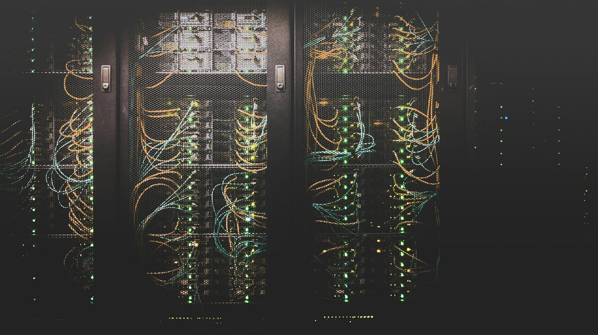 Server cabinets with bundled network cables behind mesh doors.