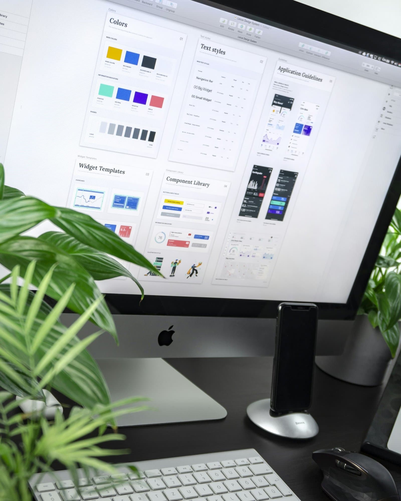 iMac on a dark desk showing a design system with color and type samples.